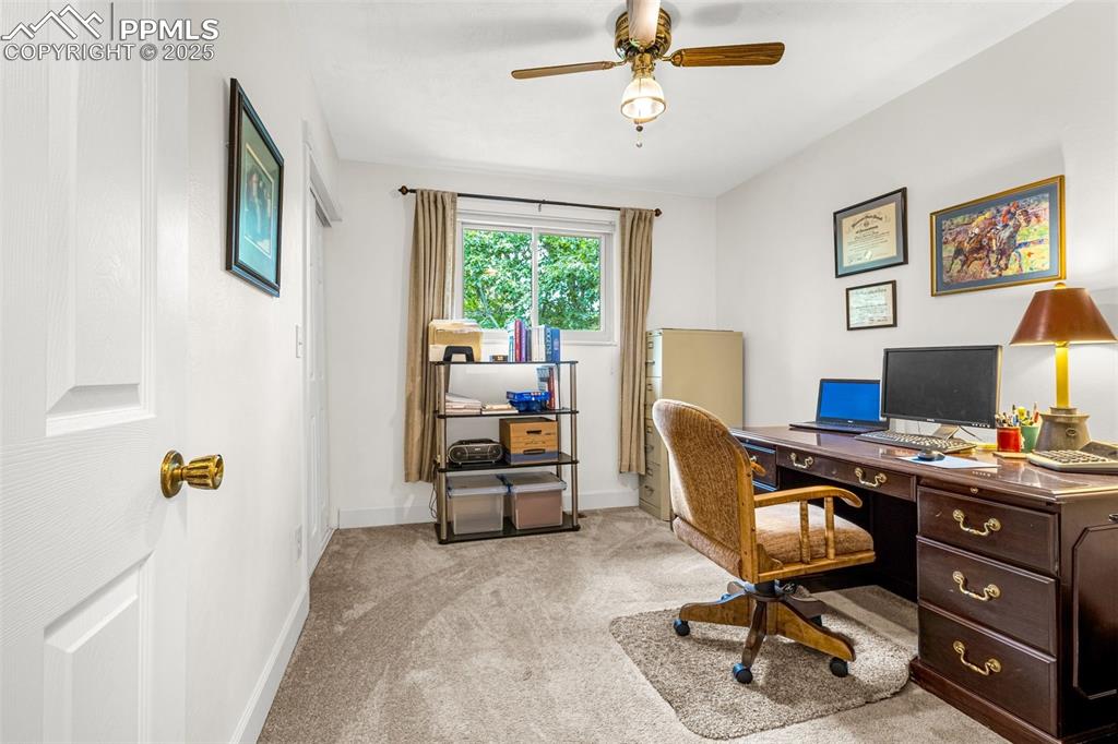 Image 14 of 33: Office with a ceiling fan and light colored carpet