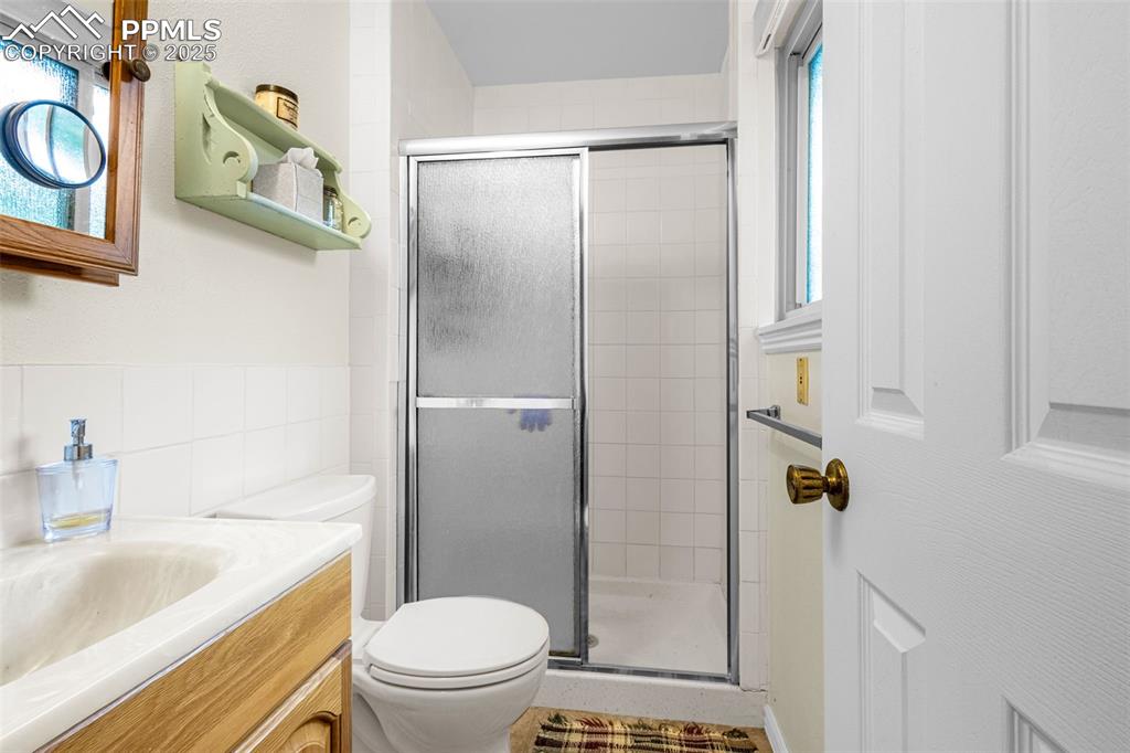 Image 17 of 33: Bathroom with a shower stall, vanity, and tile walls