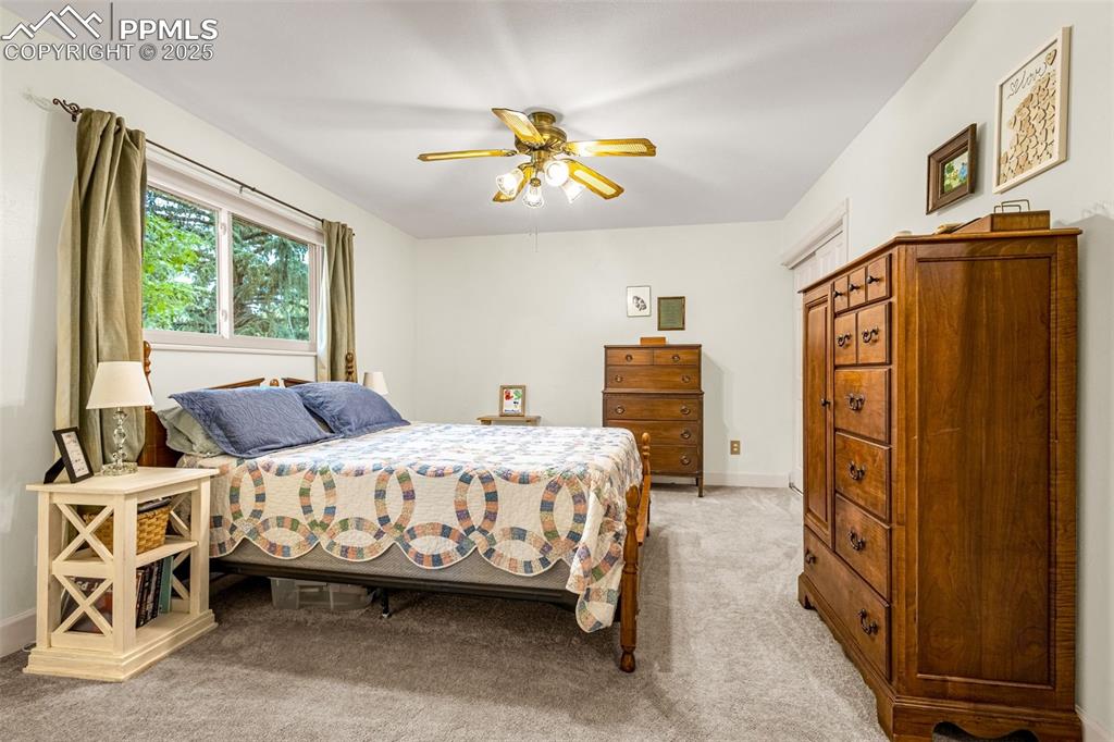 Image 18 of 33: Bedroom with light colored carpet and a ceiling fan