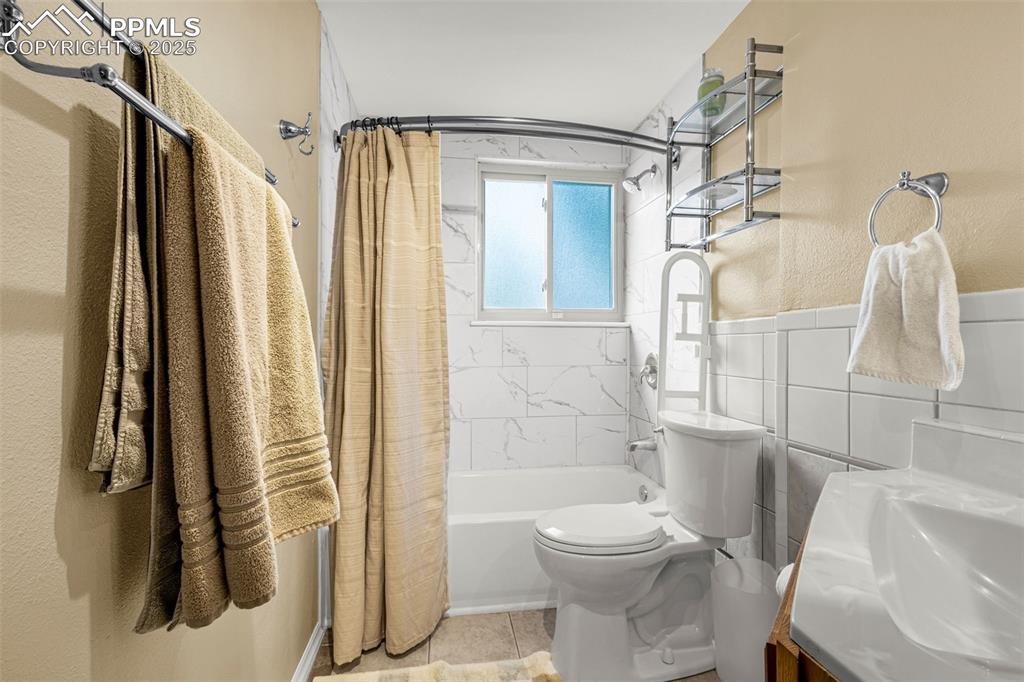 Image 20 of 33: Bathroom with shower / bath combo, vanity, tile patterned flooring, tile wa