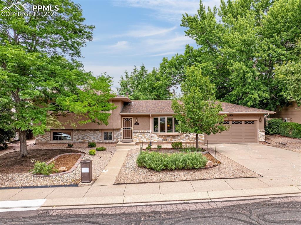 Image 26 of 33: Split level home featuring driveway, an attached garage, stucco siding, a s