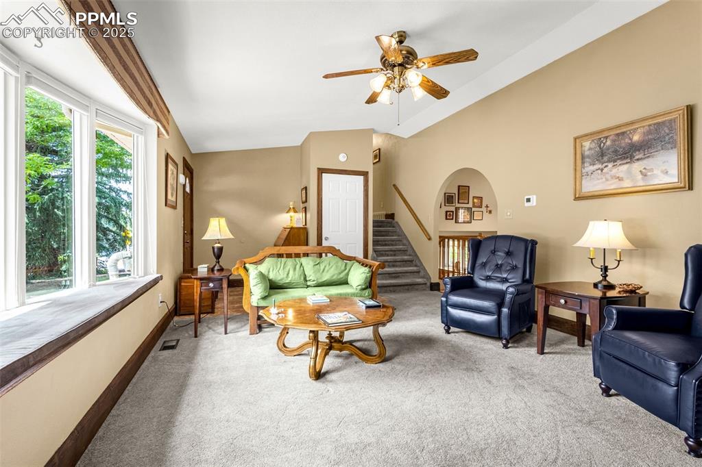 Image 5 of 33: Living room with carpet floors, a ceiling fan, lofted ceiling, and stairway