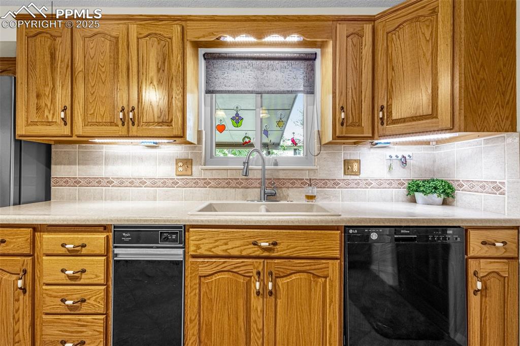 Image 7 of 33: Kitchen featuring dishwasher, brown cabinetry, decorative backsplash, and l