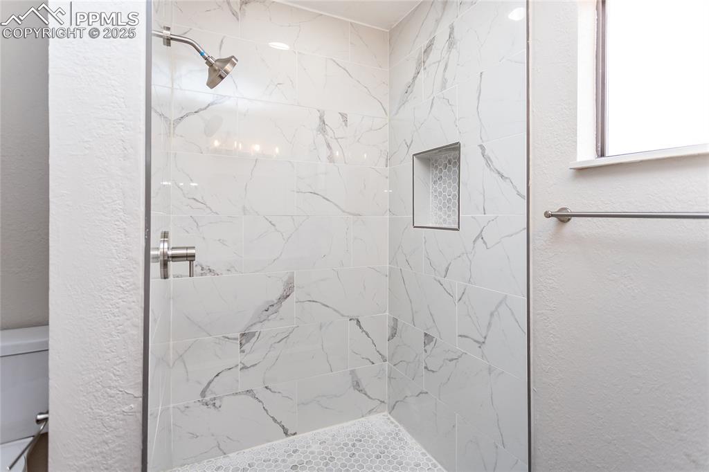 Image 33 of 50: Gorgeous porcelain tile surroun in the shower with a custom shower niche.