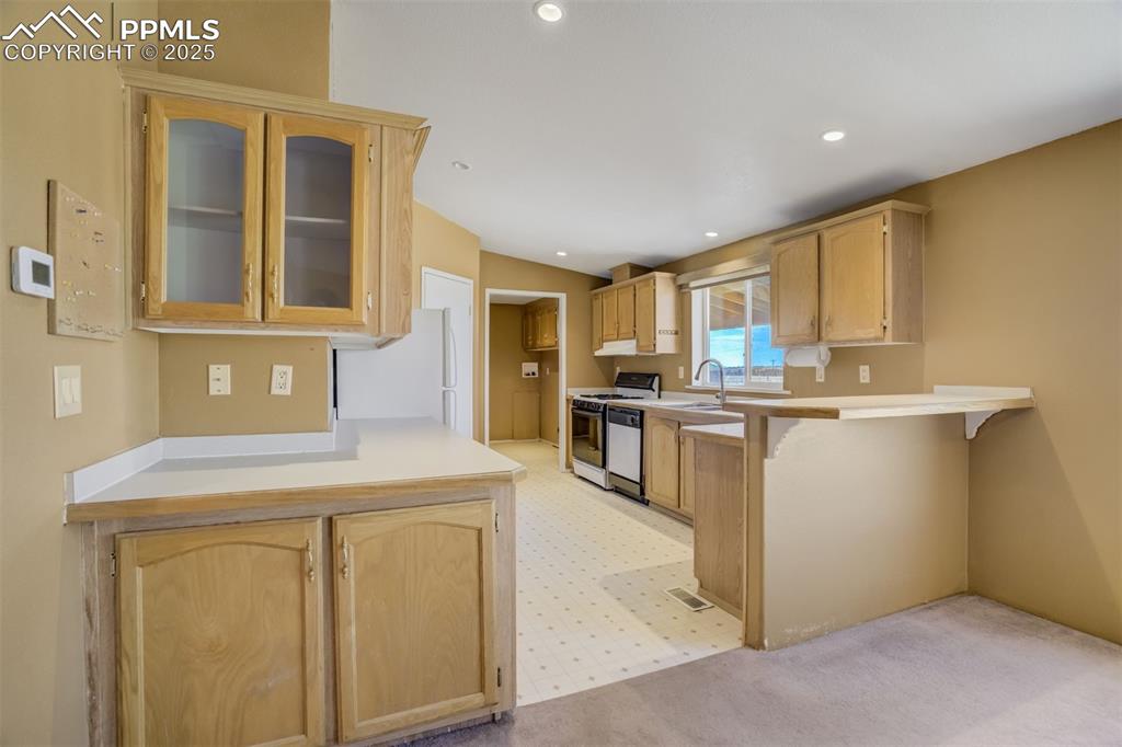 Image 16 of 50: Kitchen with a kitchen breakfast bar, white appliances, glass insert cabine