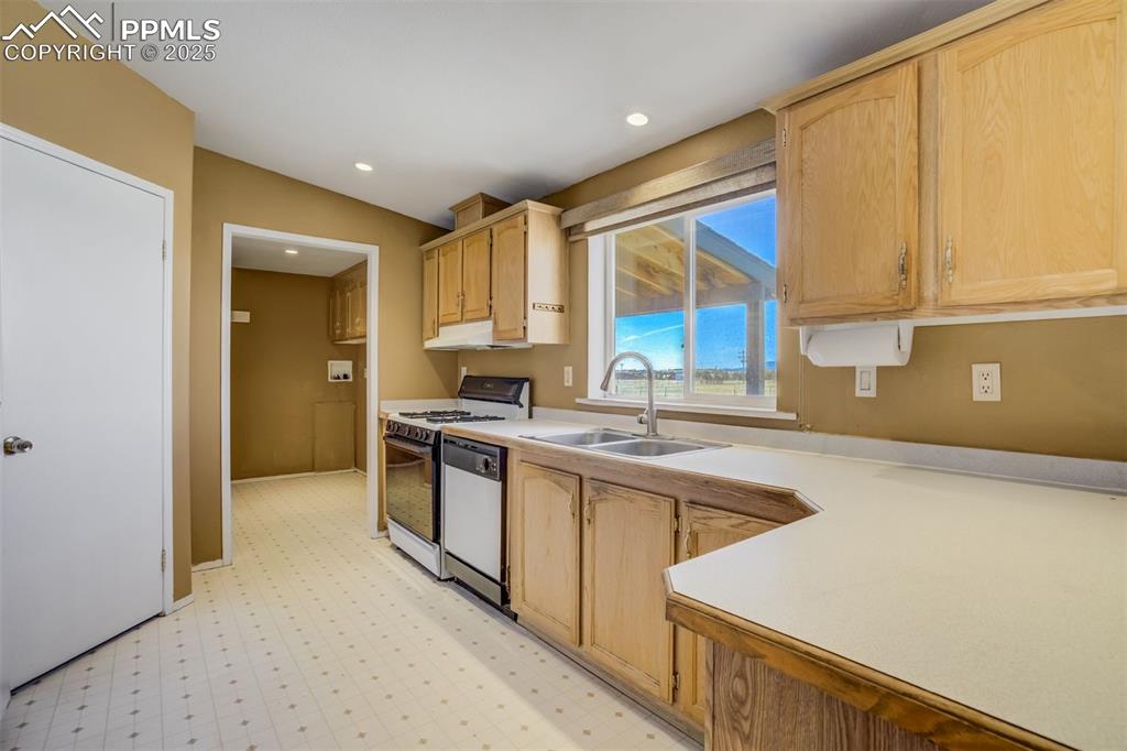 Image 17 of 50: Kitchen featuring range with gas cooktop, light brown cabinets, a sink, and
