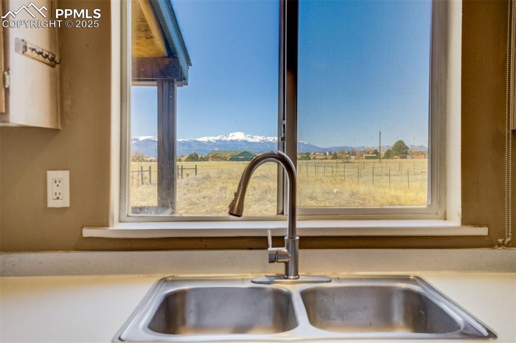 Image 18 of 50: Details with a rural view, a mountain view, a sink, and light countertops