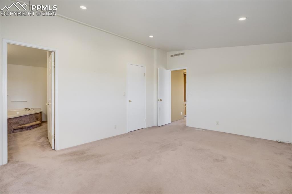 Image 24 of 50: Unfurnished bedroom with light carpet, connected bathroom, visible vents, a