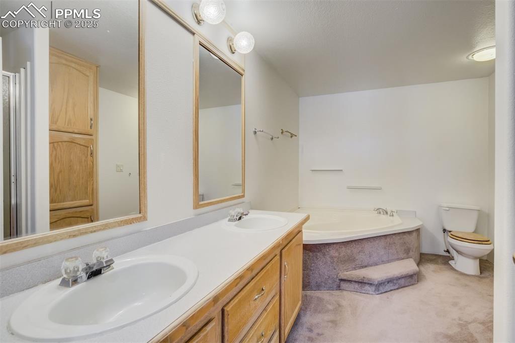 Image 25 of 50: Bathroom with a sink, toilet, double vanity, and a garden tub