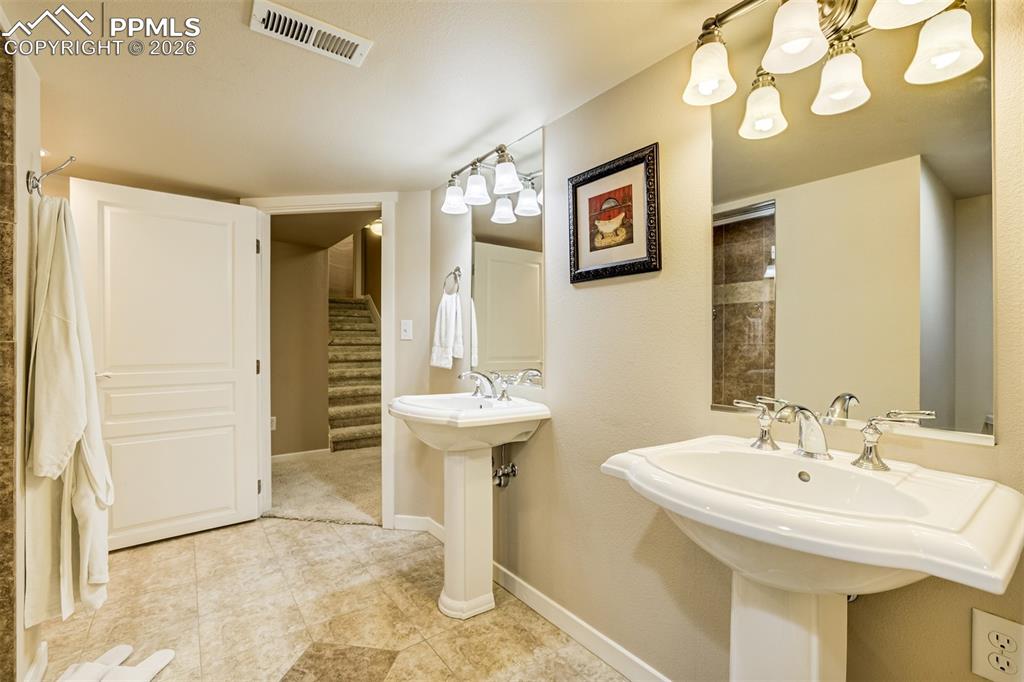 Image 41 of 50: A 3/4 bathroom in basement with two pedestal sinks