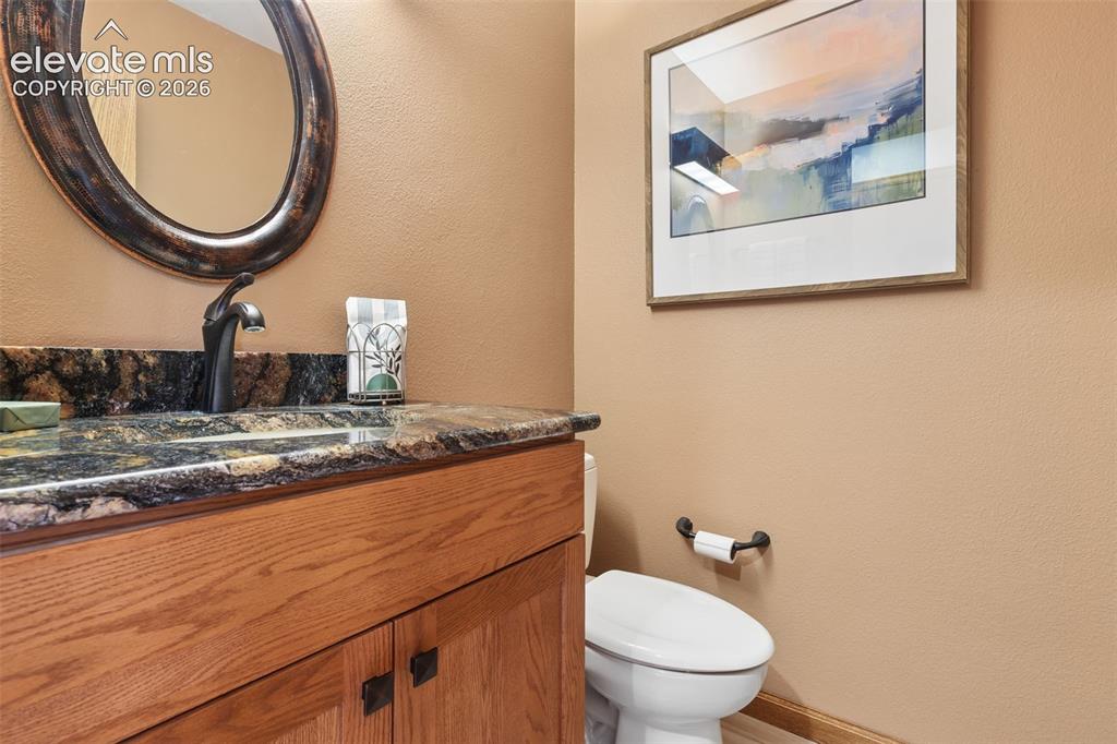 Image 16 of 41: 1/2 bath off the kitchen with granite counters and decorative lighting.