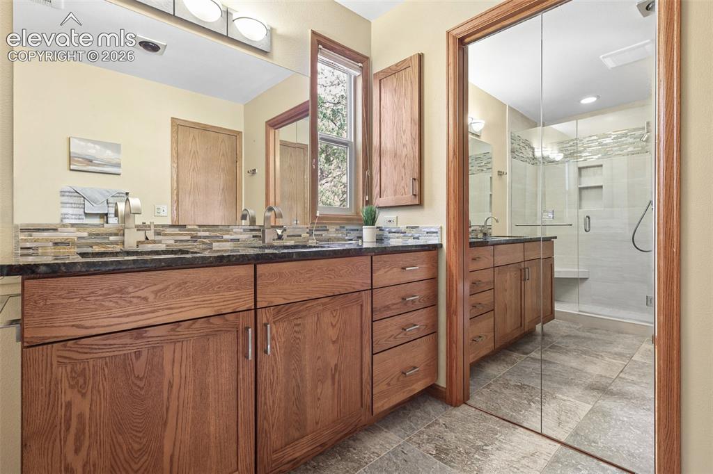 Image 19 of 41: Primary remodeled bath features double sinks, granite counters, and stone f