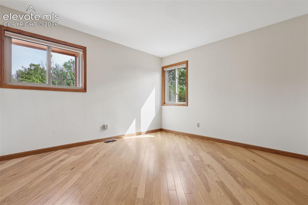 Image 22 of 41: 2nd bedroom with hardwood flooring and closet with built-in shelving.
