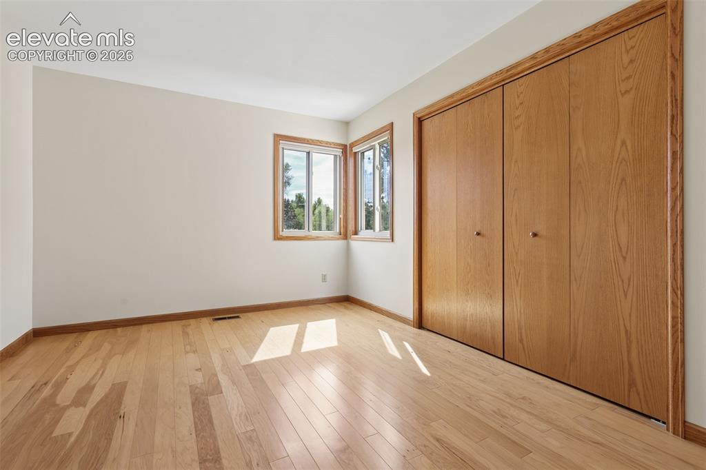 Image 24 of 41: 3rd spacious bedroom with hardwood flooring closet with built-in shelving.