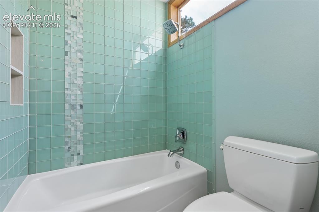 Image 26 of 41: Remodeled bath featuring beautiful glass tile with granite counters, double