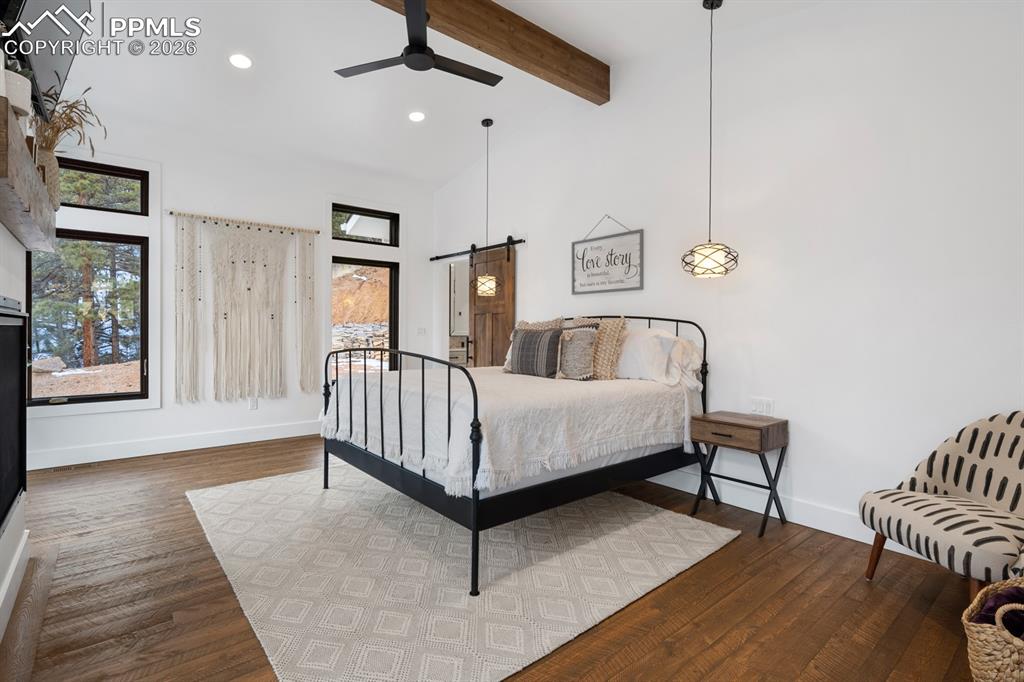 Image 12 of 30: The main-level primary suite includes a fireplace and sliding doors to the 