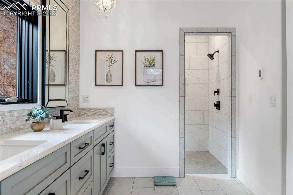 Image 15 of 30: A spa-like bathroom with heated tile floors, double quartz vanity, designer