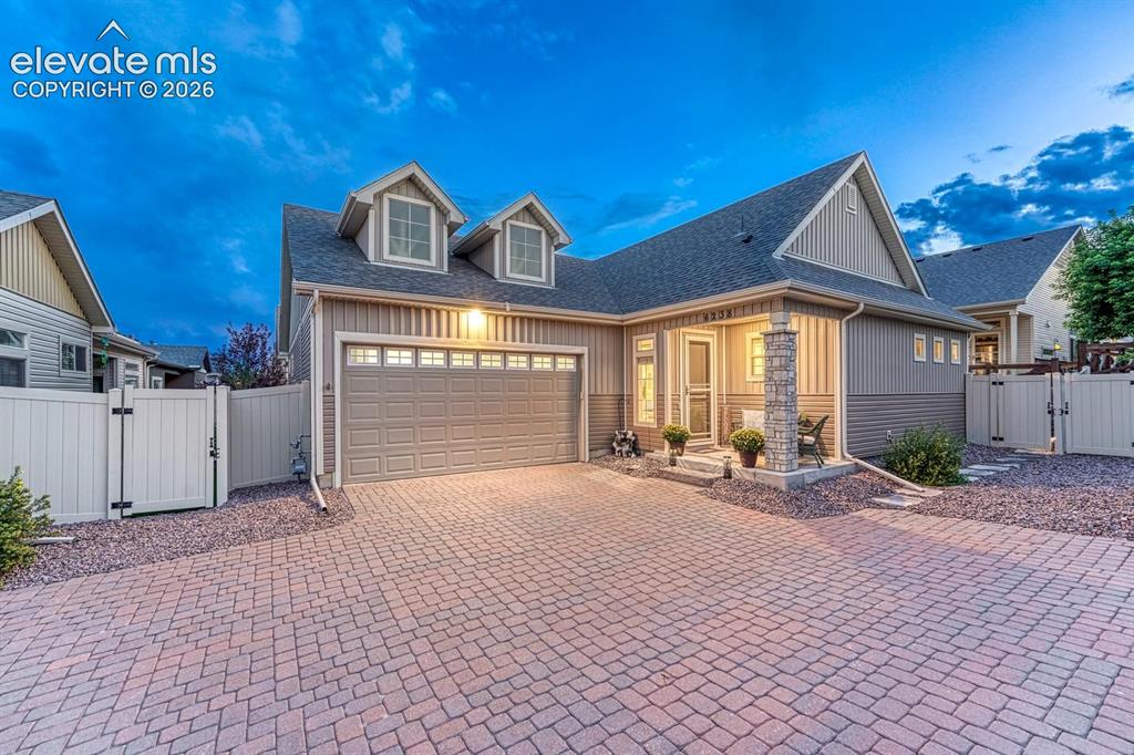 Image 1 of 44: Paved driveway, attached garage, stone column accents, dormer windows, and