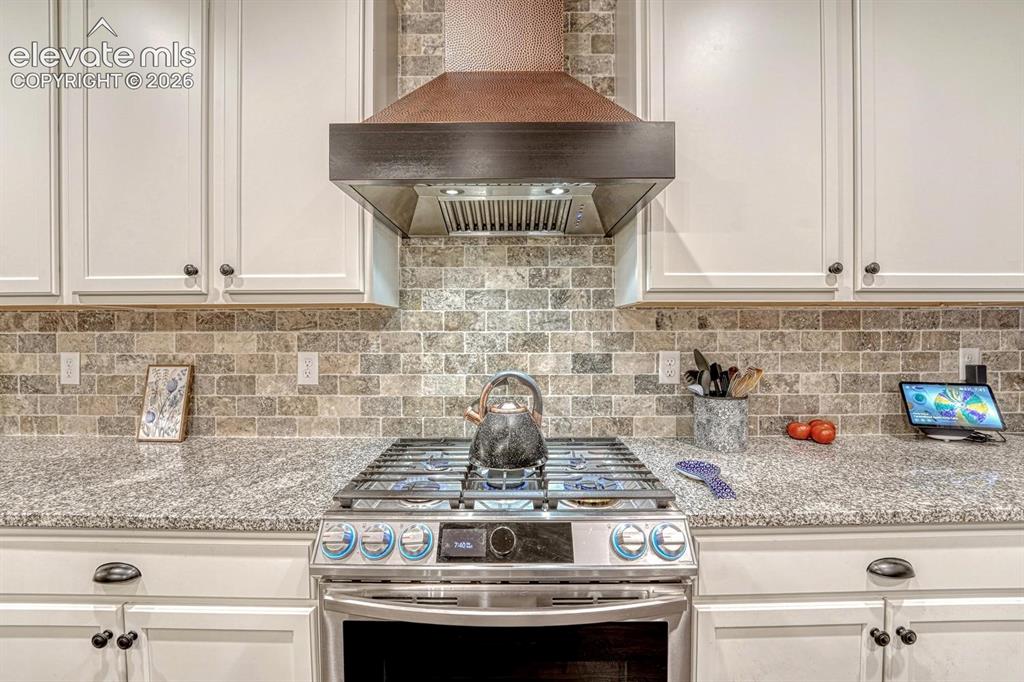 Image 10 of 44: Stainless steel gas range with coordinating ventilation hood, stone mosaic 