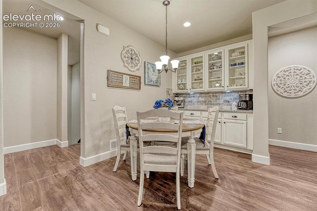 Image 11 of 44: Wood-finish flooring, recessed lighting, built-in cabinetry with glass fron