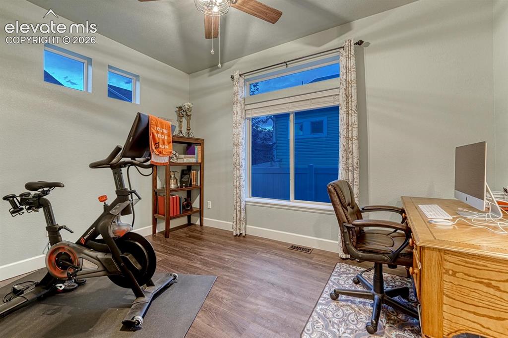 Image 27 of 44: Wood-finish flooring, ceiling fan, large window with blinds, and built-in s