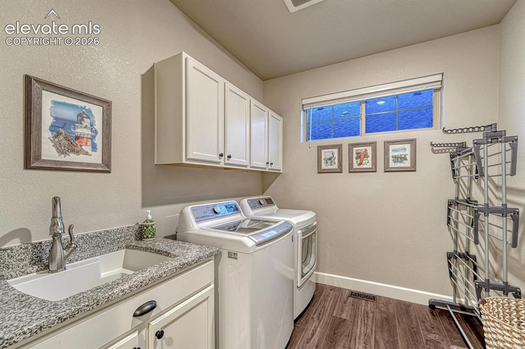 Image 28 of 44: Laundry area with white cabinetry, a utility sink, granite-style countertop