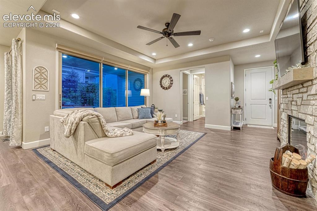 Image 4 of 44: Living space with wood-finish flooring, recessed lighting, and a stone-clad