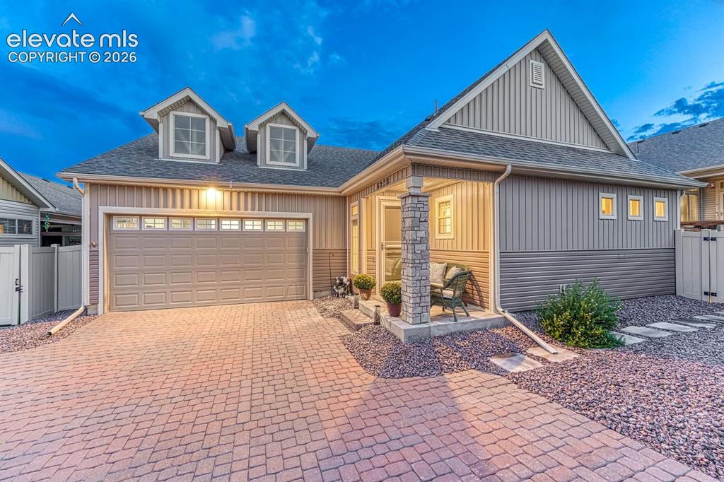 Image 44 of 44: Exterior featuring a paver driveway, an attached garage, a covered front po