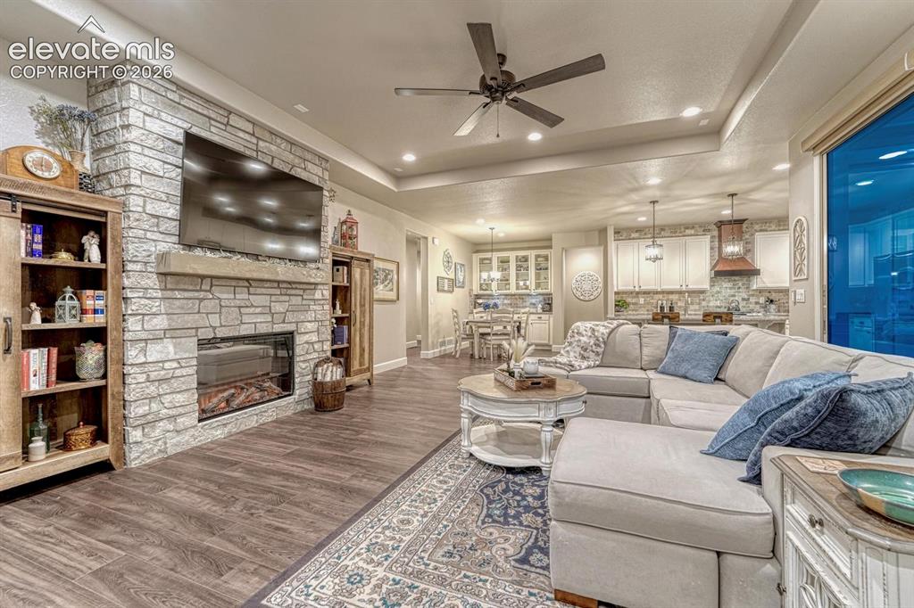 Image 5 of 44: Stone-clad fireplace with mantel, recessed ceiling lighting, wood-finish fl