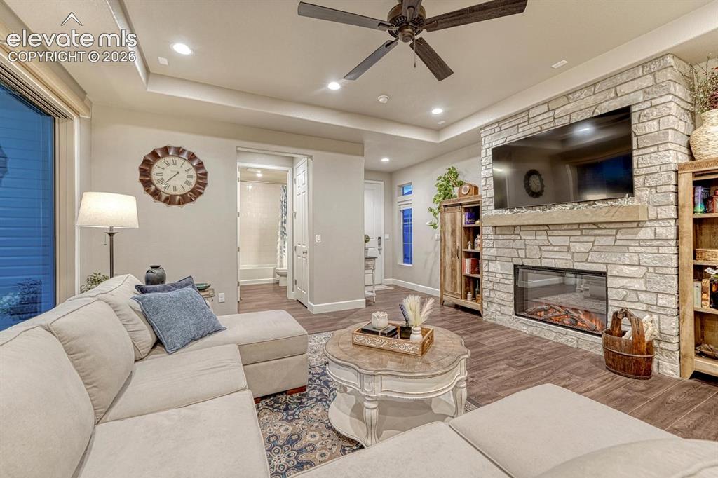Image 6 of 44: Stacked stone fireplace with a wood mantel, wood-finish flooring, recessed