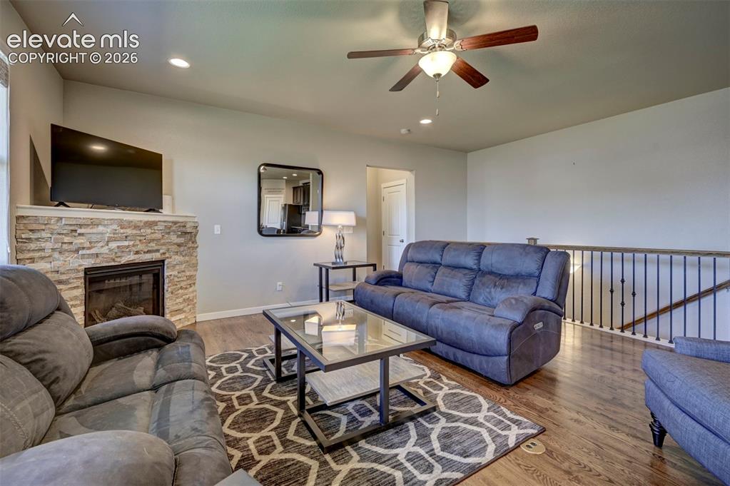 Image 13 of 40: Stacked stone fireplace, recessed lighting, ceiling fan, wood-finish floori