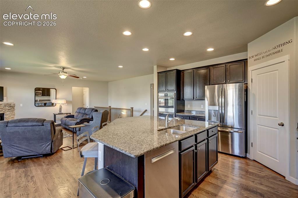 Image 18 of 40: Open-concept living space featuring a kitchen island with dual sinks, stain