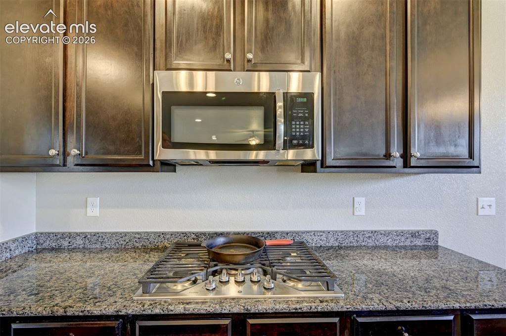 Image 19 of 40: Dark wood-finish cabinetry with decorative hardware, stainless steel over-t