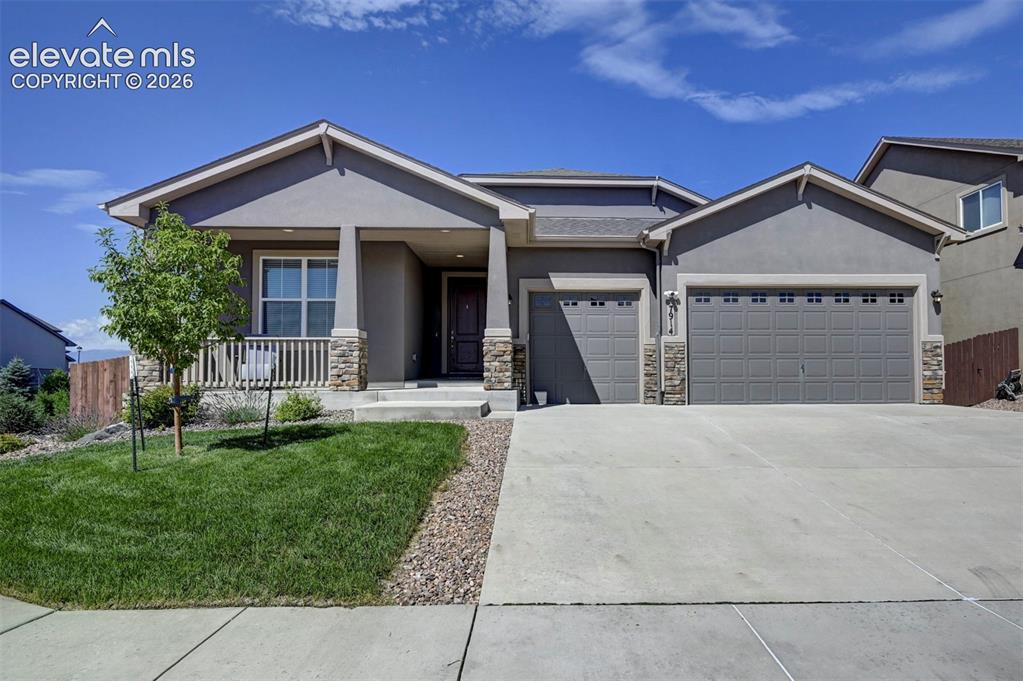 Image 2 of 40: Stucco exterior with stone accents, covered front porch, two-car garage, an