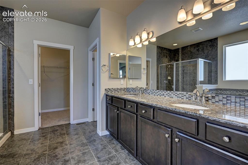 Image 25 of 40: Dual vanity with under-mount sinks, a mosaic tile backsplash, and dark wood