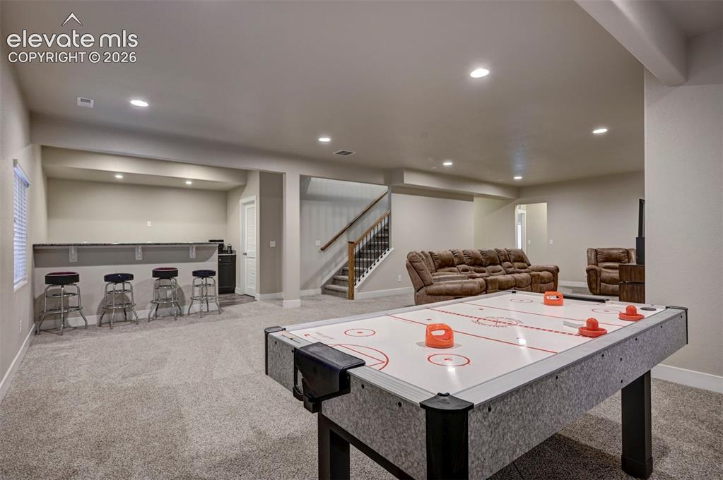 Image 31 of 40: Spacious recreation room featuring recessed lighting, a built-in bar with a