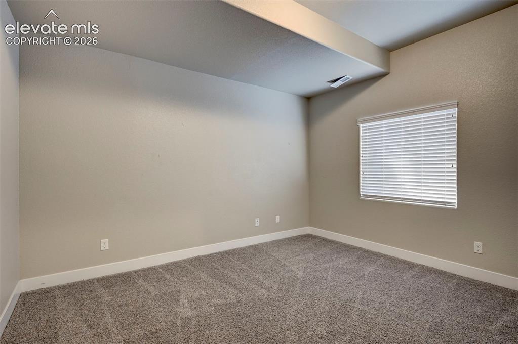 Image 37 of 40: Carpeted room with neutral wall tones and a single window featuring horizon