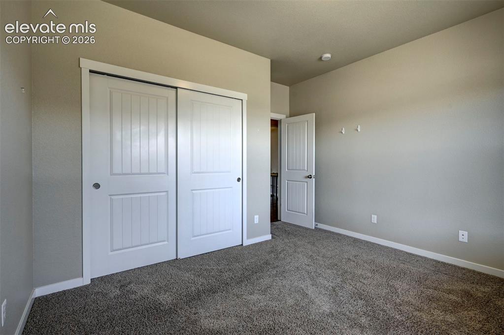 Image 5 of 40: Neutral-toned walls, gray carpet flooring, white paneled closet doors, whit