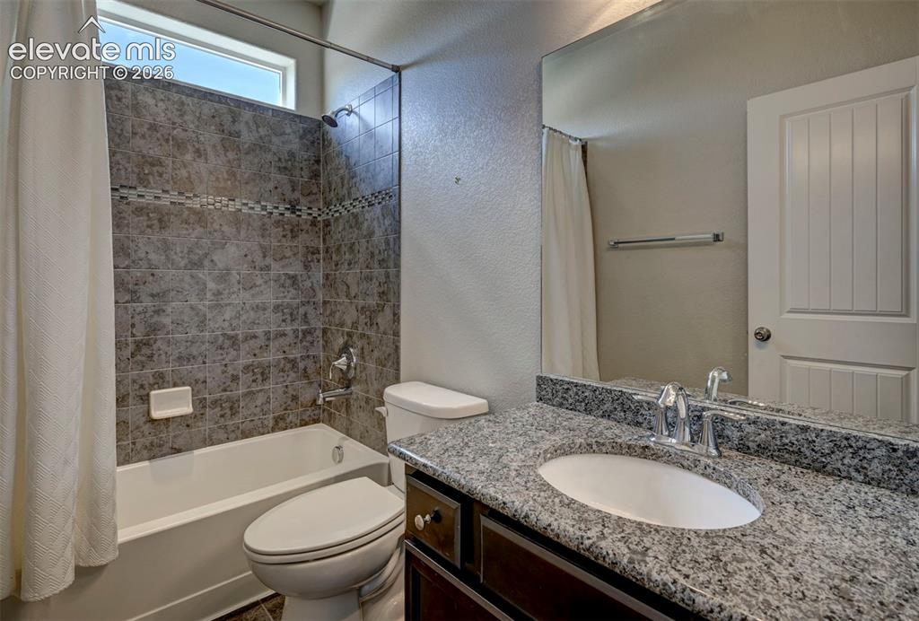 Image 6 of 40: Bathroom featuring a shower-tub combination, dark-toned tile surround with 