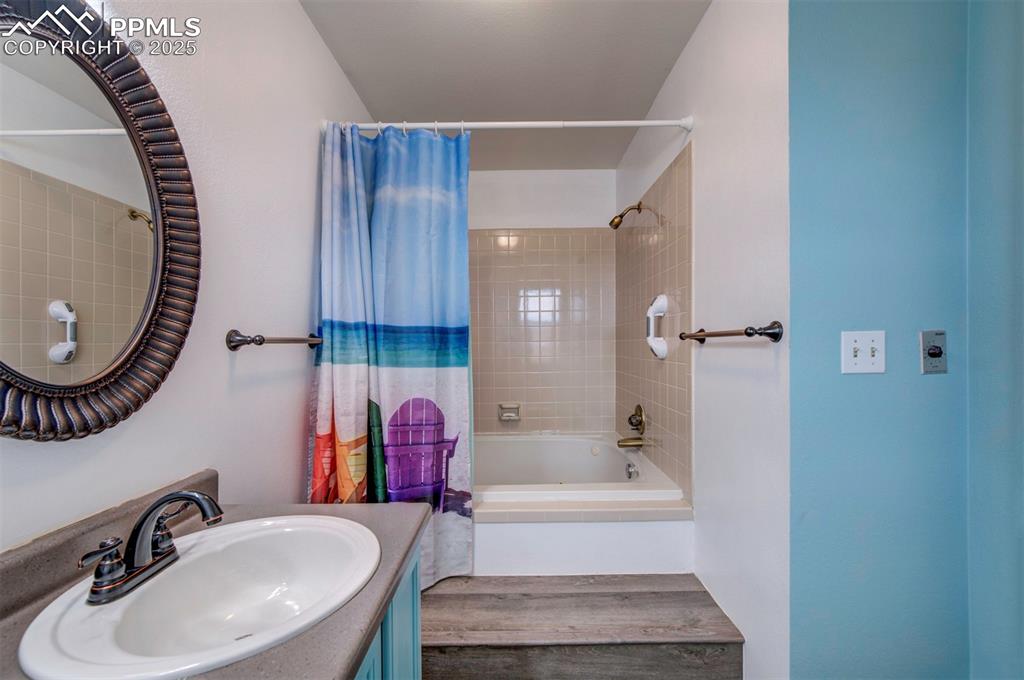 Image 24 of 50: Bathroom with vanity and shower / bathtub combination with curtain