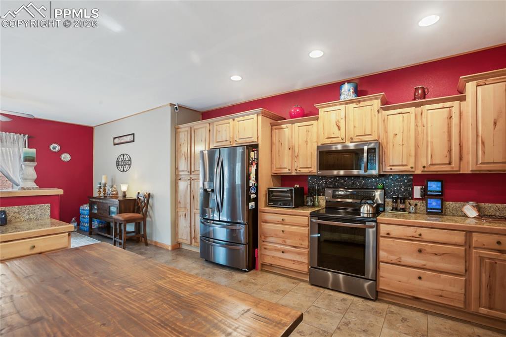 Image 8 of 33: The kitchen featuring stainless steel appliances,  pine cabinets, granite c