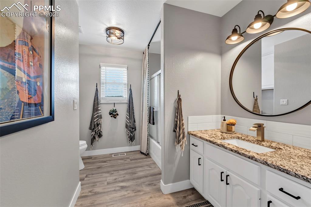 Image 18 of 50: A large shared full bath is located next to the laundry on the main level. 