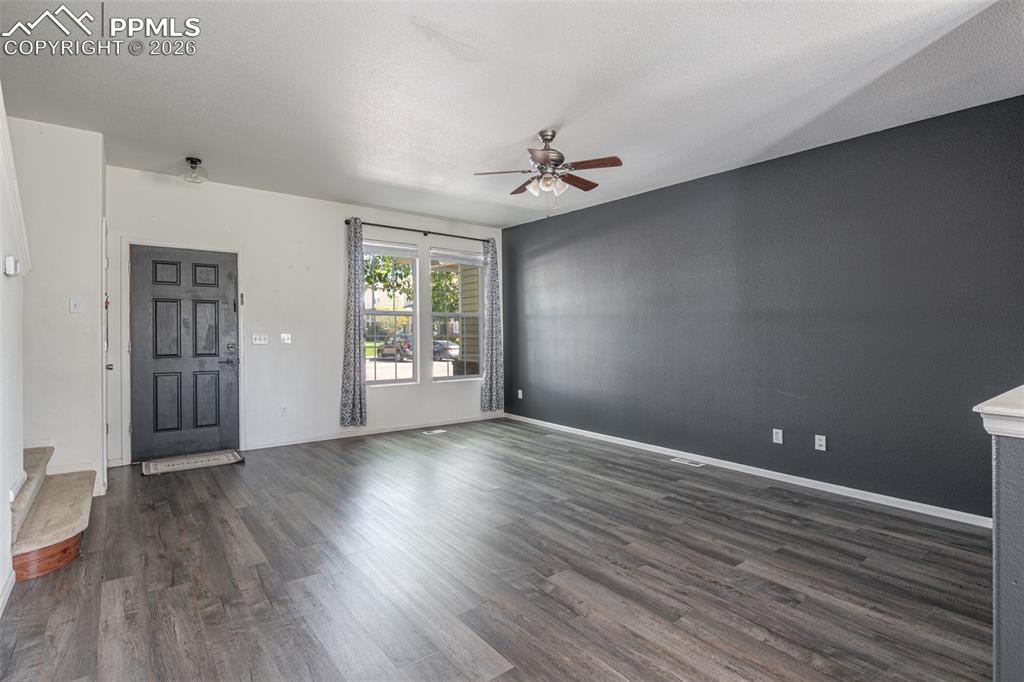 Image 8 of 34: Unfurnished living room featuring dark wood finished floors and a ceiling f