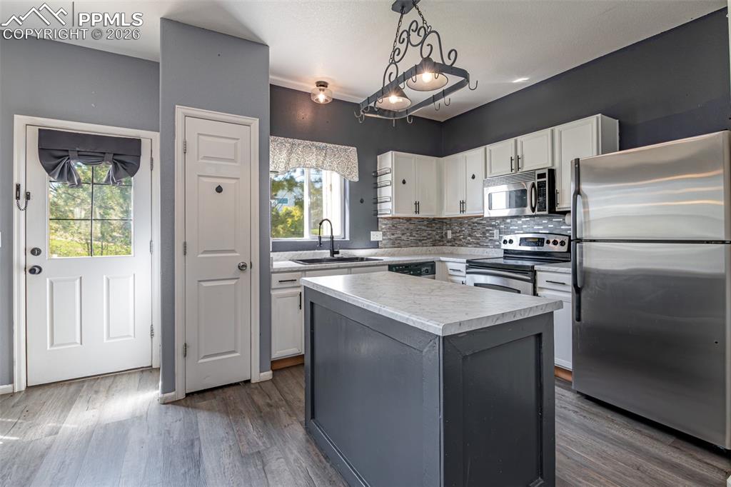 Image 9 of 34: Two tone kitchen with stainless steel appliances, decorative backsplash, li