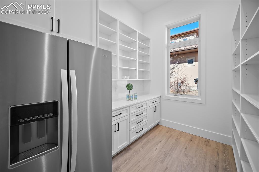Image 10 of 43: Walk-in pantry with custom cabinetry and fridge