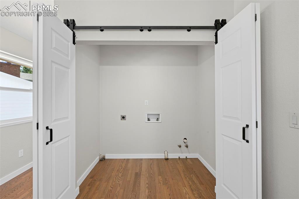 Image 11 of 48: laundry with a barn door/bi-fold, washer hookup, dryer hookup, and wood fin