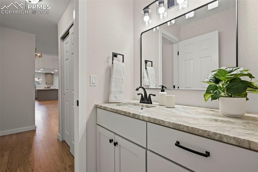 Image 20 of 48: Bathroom with wood finished floors, vanity, and a textured wall