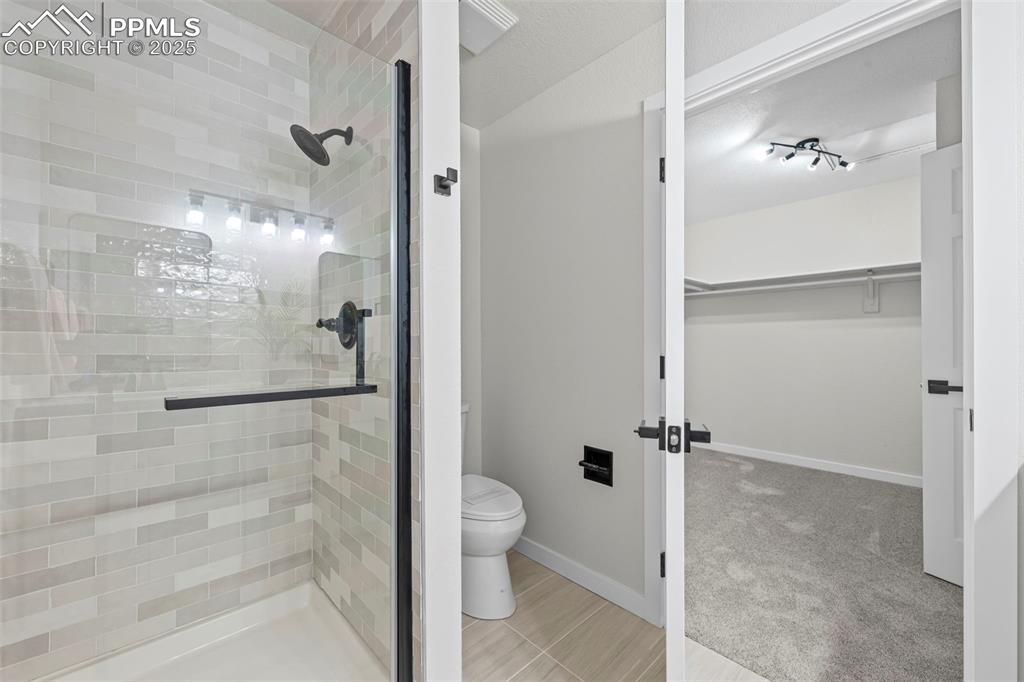 Image 25 of 48: Full bathroom featuring a stall shower and a spacious closet
