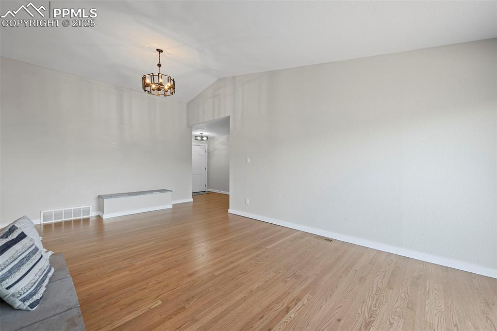 Image 4 of 48: Unfurnished living room featuring lofted ceiling, a chandelier, and light w
