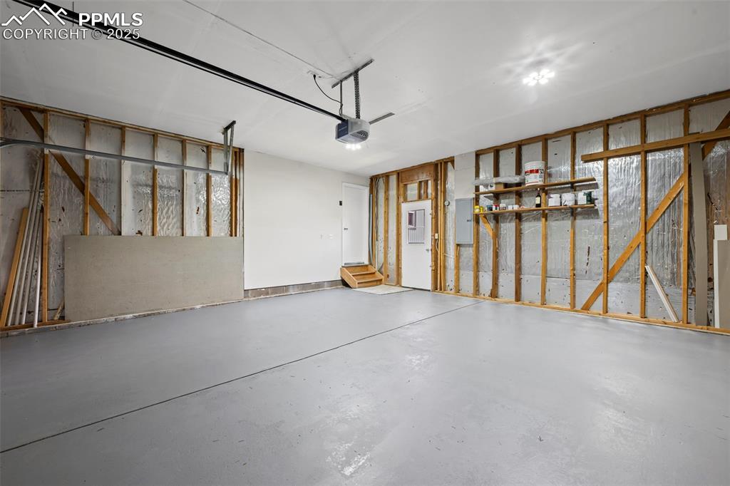 Image 46 of 48: Garage with a garage door opener and electric panel